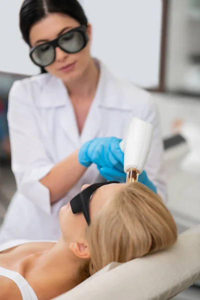 Mujer rubia acostada en un sofá recibiendo tratamiento facial . — Foto de Stock