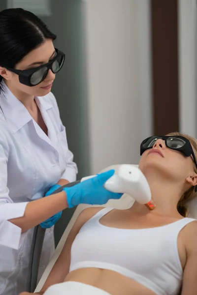 Cosmetólogo y su cliente durante el procedimiento láser . — Foto de Stock