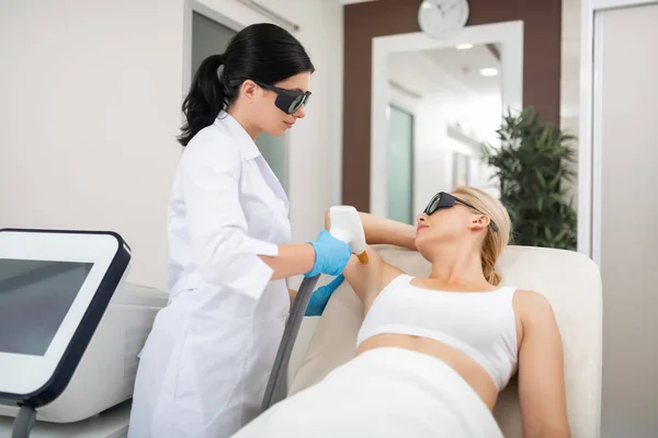 Kosmetolog dając jej klienta laserowe leczenie pachy skóry. — Zdjęcie stockowe