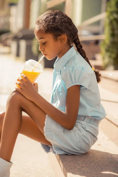 细心的黑皮肤女孩喝美味的橙汁 — 图库照片