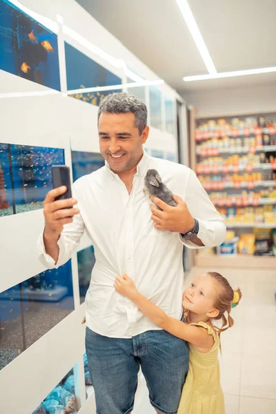 Daughter hugging daddy making selfie with rabbit