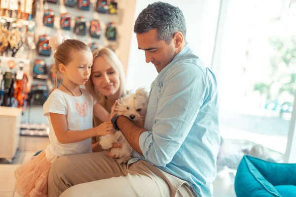 Parents and their cute girl taking fluffy white dog to the pet shop