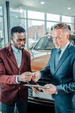 Yeni araba kullanan bir sözleşme sonuçlandıran adam.