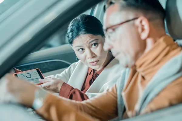 Woman asking her husband questions about their car.