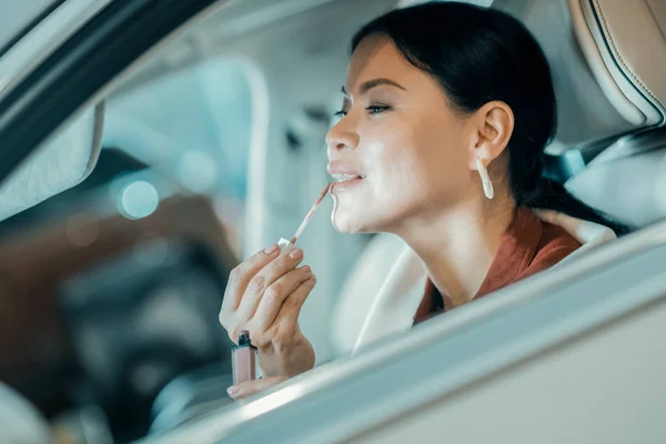 Kobieta oddanie na jej szminki w samochodzie. — Zdjęcie stockowe