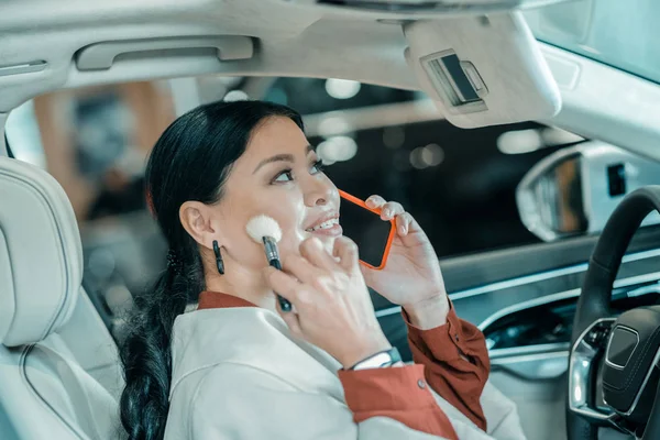 Woman talking on her phone putting on make-up. — Stock Photo, Image