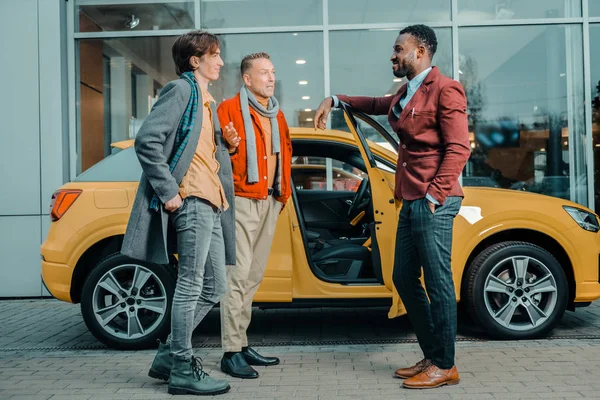 Dos hombres hablando con un concesionario de coches después de comprar automóviles . — Foto de Stock