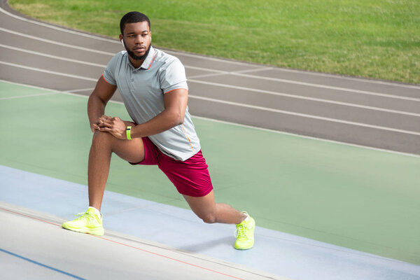 Handsome male athlete warming up before workout at the stadium