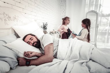 Onu uyandırmak üzere olan iki çocuğuyla uyuyan baba