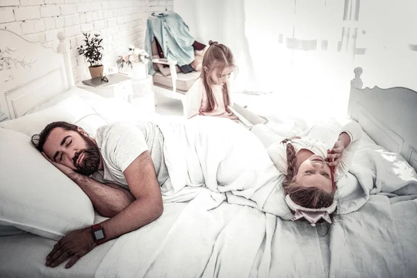 Padre durmiendo mientras sus hijos juegan en la cama — Foto de Stock