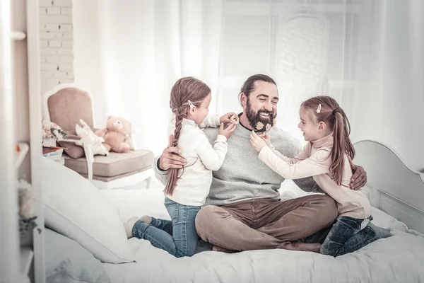 Baba ve iki kızı yatakta birlikte oynarken oturuyorlar. — Stok fotoğraf