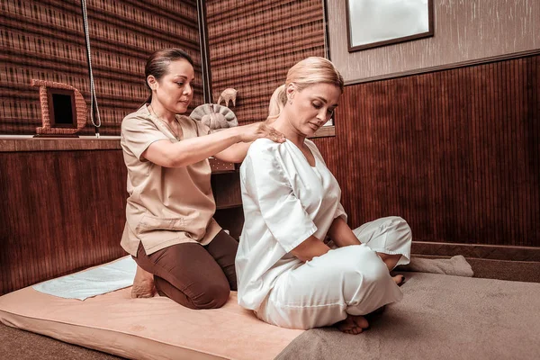 Profesjonalna masażystka pracując z ramionami swojego klienta. — Zdjęcie stockowe