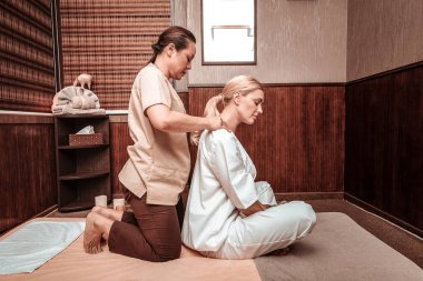 Güzel kadın salonda omuzmasajı oluyor.