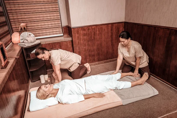 Dos mujeres haciendo masajes para su cliente . — Foto de Stock