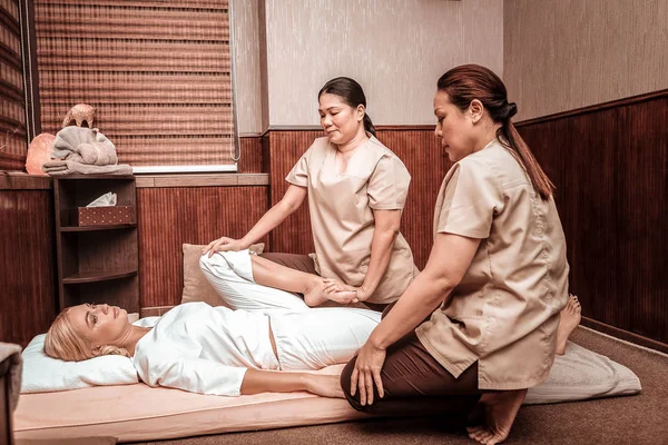 Twee masseuses doen beenmassage voor hun cliënt. — Stockfoto