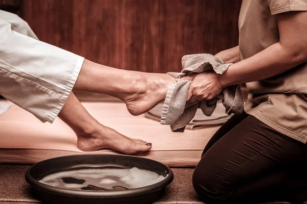 Masażyuse wycieranie nogi z jej klient po mycie. — Zdjęcie stockowe