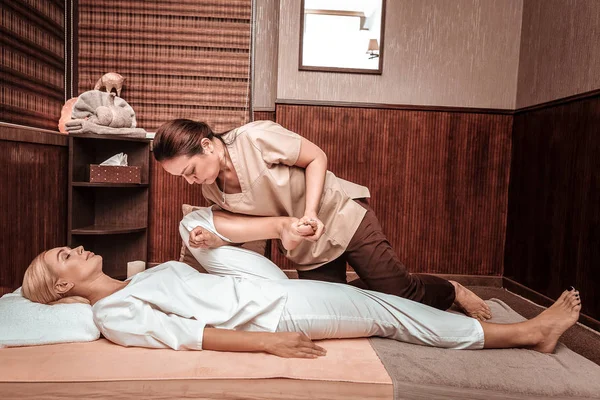 Strong masseuse doing thai massage for her client.