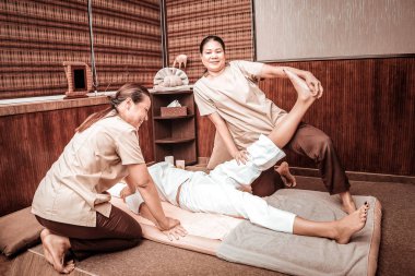 Müvekkilleri için bacakları geren iki masöz.