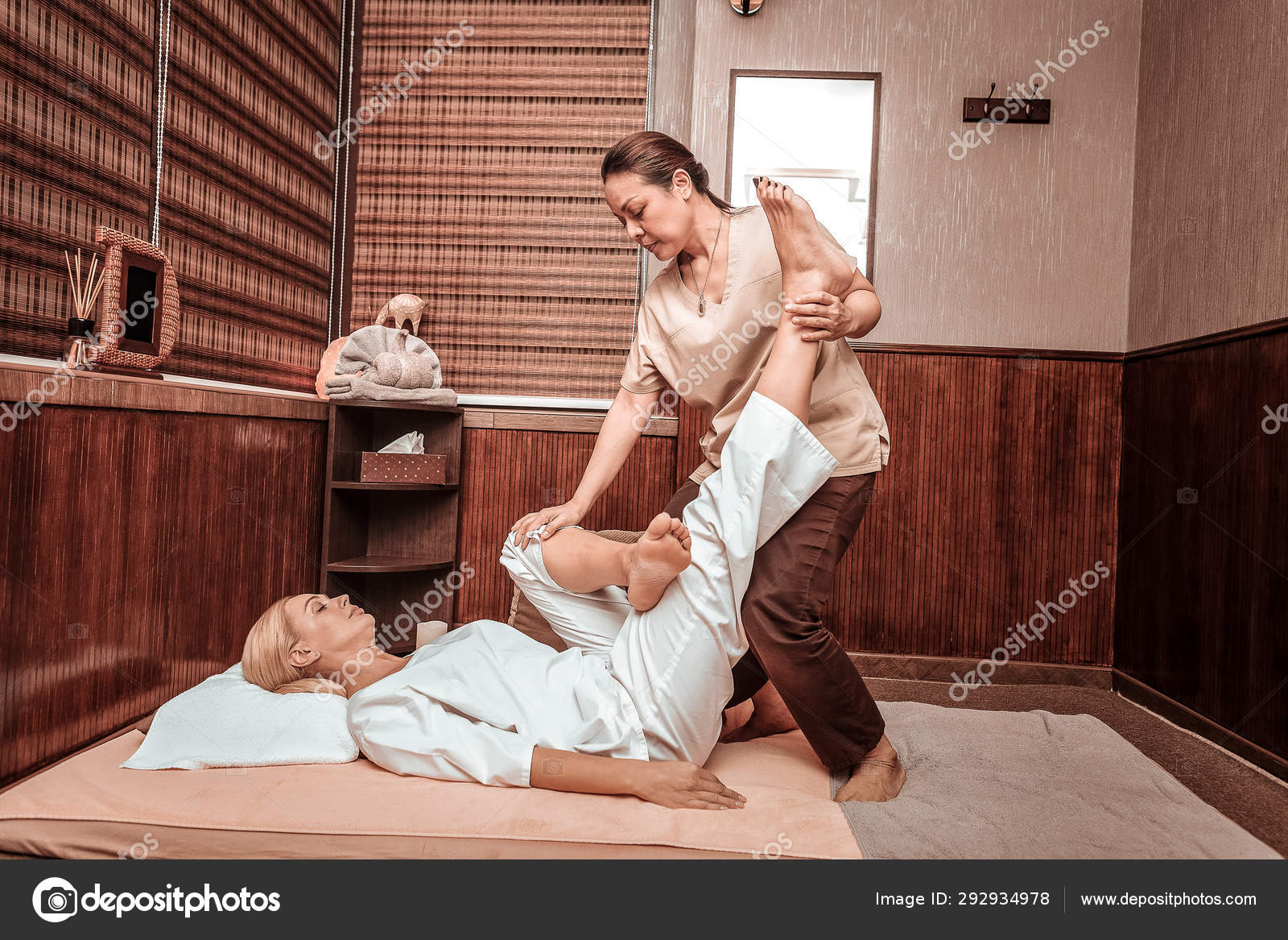 Mestre feminino qualificado mestre profissional forte fazendo massagem nas  pernas para cliente feminino
