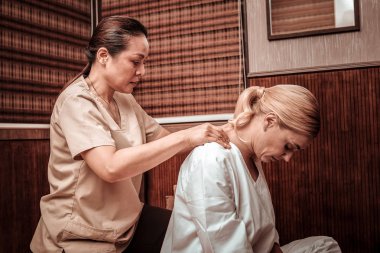 Profesyonel masöz müşteri boyun masajı yapıyor.