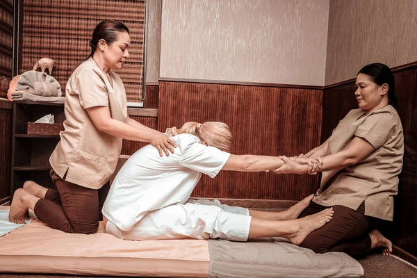Zwei masseurinnen stratching rückseite von ihre client. — Stockfoto