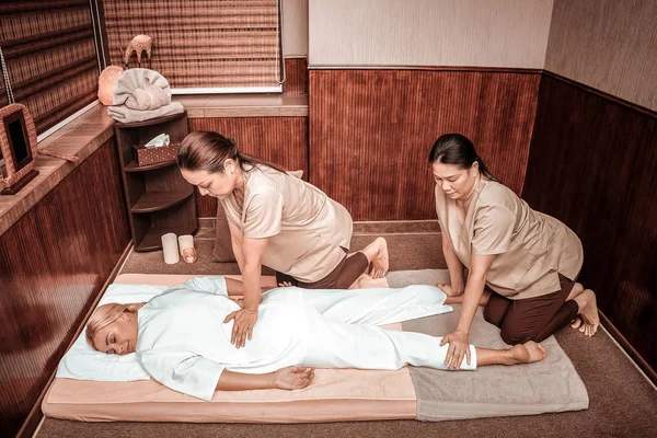 Woman getting back massage by two masseuses. — Stock Photo, Image
