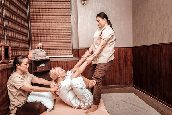 Massagista puxando as mãos de seu cliente durante a massagem . — Fotografia de Stock