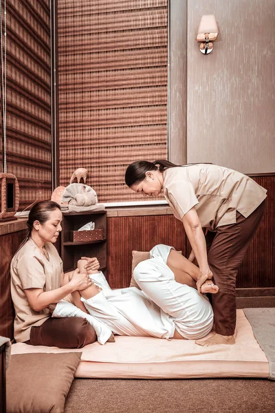 Woman getting her thai massage by two masseuses. — Stock Photo, Image