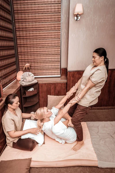 Two women doing thai massage for their client. — Stock Photo, Image