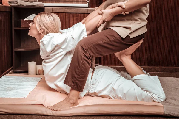 Mulher endireitando as costas durante a sessão de massagem . — Fotografia de Stock