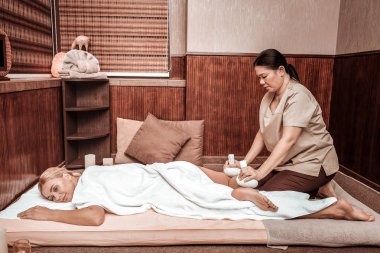 Gülümseyen kadın çantası masaj sırasında bir paspas üzerinde yatan.