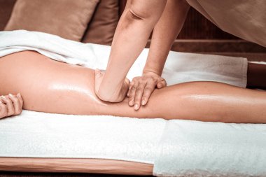 Masaj salonu istemcisi için yağ ile rahatlatıcı bacak masajı.
