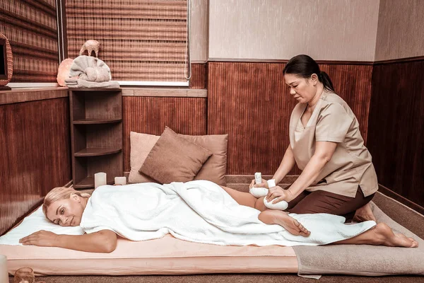 Lachende vrouw liggend op een mat tijdens haar zak Massage. — Stockfoto