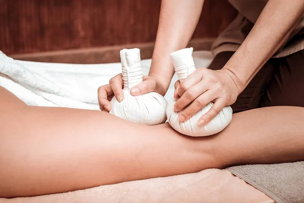 Herbal Bag massage van benen in massagesalon. — Stockfoto