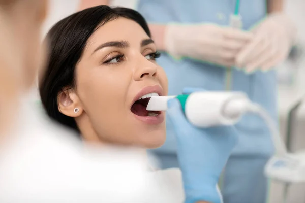 Hermosa mujer cuidando sus dientes en el consultorio de dentistas . — Foto de Stock