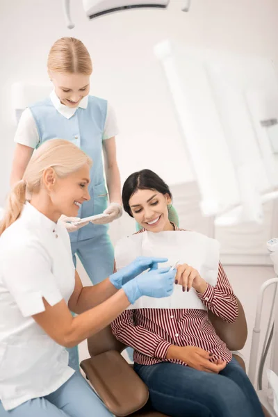 Dentysta pokazujący jej próbki do wybielania zębów pacjenta. — Zdjęcie stockowe