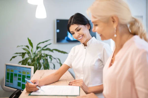 Frau und ihr Zahnarzt füllen gemeinsam das Formular aus. — Stockfoto