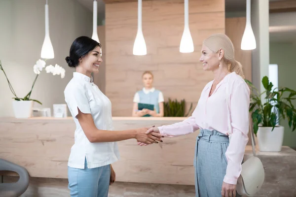 Fröhliche Frau verabschiedet sich von ihrem Zahnarzt. — Stockfoto