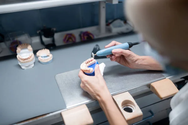 Dental technician doing denture polishing in her office. — Stock Photo, Image