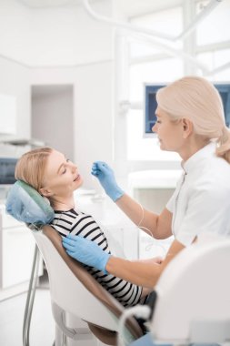 Diş tedavisi sırasında gülümseyen genç kadın.