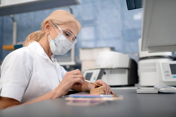 Dental technician making artificial teeth in laboratory.