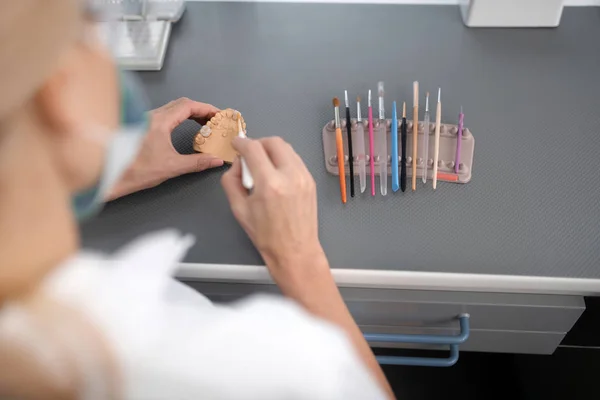 Técnico dental que usa cepillos para limpiar prótesis de porcelana . — Foto de Stock