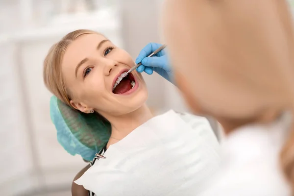 Tandläkare kontrollera hängslen av hennes glada patient. — Stockfoto