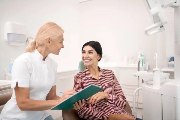 Vrouw deelt haar informatie met de tandarts. — Stockfoto