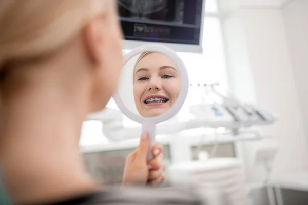 Jonge vrouw glimlachend op zoek in de spiegel. — Stockfoto