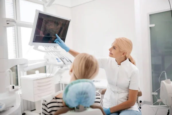 Dentysta i jej pacjent patrzą razem na x-ray. — Zdjęcie stockowe