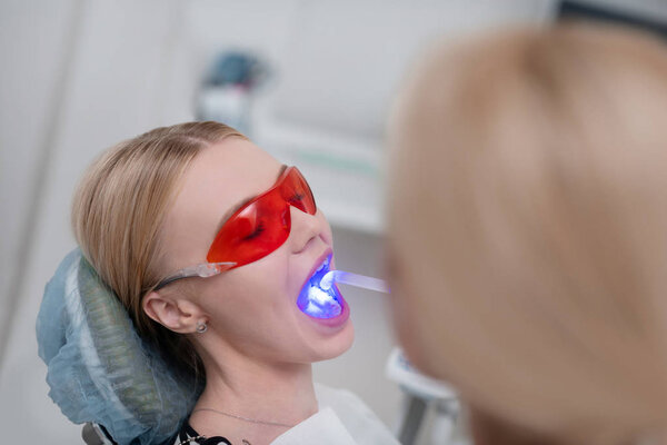 Dentist using ultraviolet lamp for patients tooth filling.