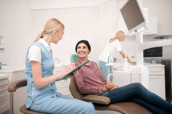 Assistent tandartsen die hun patiënt verschillende vragen stellen. — Stockfoto