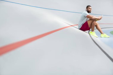 Stadyumda oturan sakin genç atletik adam