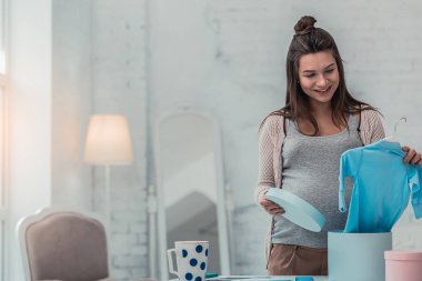 Çocuk kıyafetlerine bakan büyüleyici hamile kadın